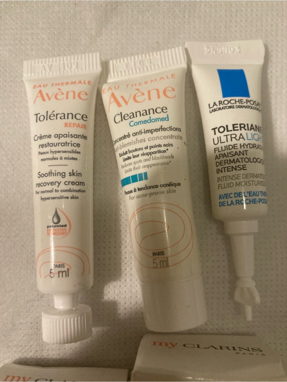 Clarins white skincare tubes with orange and blue accents